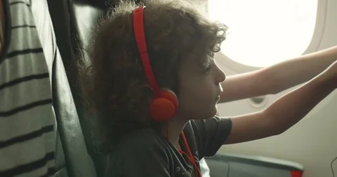 Young boy trying to adjust his seat back entertainment touchscreen on a plane Video stock 107457119