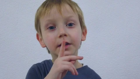 Young boy trying to attract attention surreptitiously, gesticulating his face Stock Footage 125526899