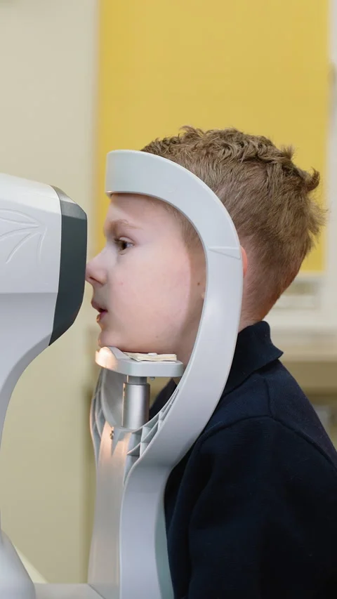 Young boy undergoing autorefractor eye exam Stock Footage 310811993