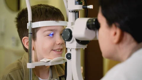 Young boy undergoing eye examination with slit lamp by optometrist Stock Footage 310808507