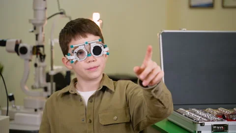 Young boy undergoing eye examination pointing finger during vision test Stock Footage 310810048