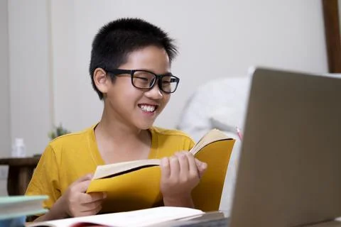 Young boy using computer and mobile device studying online. Stock Photos