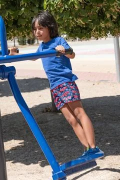 Young boy using an elliptical machine in a playground Stock Photos