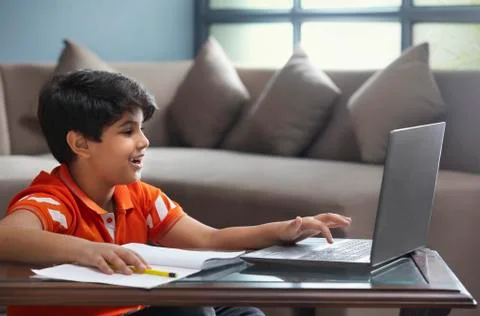 A YOUNG BOY USING LAPTOP TO ATTEND ONLINE CLASS	 Stock Photos