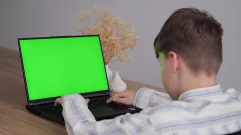 A young boy is using a laptop computer with a green screen Stock Footage 273042165