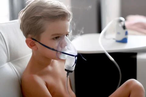 Young boy using nebulizer for asthma and respiratory diseases at home. Teenager Stock Photos