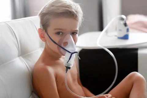 Young boy using nebulizer for asthma and respiratory diseases at home. Teenager Stock Photos