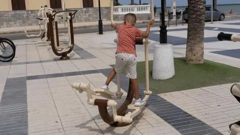 Young Boy Using Outdoor Exercise Equipment in Public Park Photos