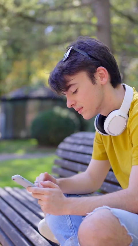 Young boy using phone in a park Stock Footage 252641122