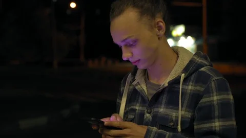 Young boy using smartphone outdoors at night, milticolor screen light, 4k 7 Stock Footage 95425289