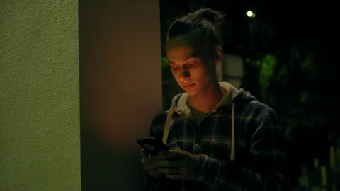 Young boy using smartphone outdoors at night, milticolor screen light, 4k 4 Video stock 95425354