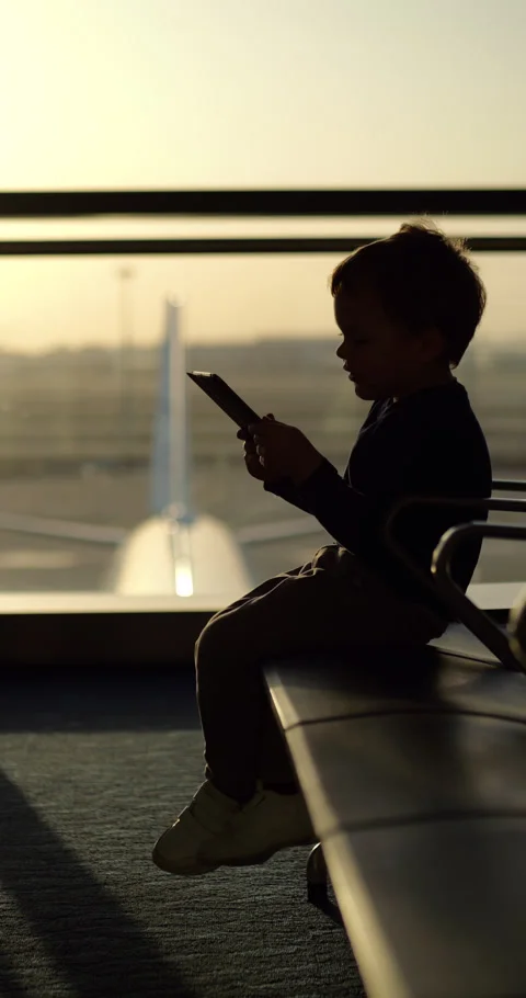 Young boy using tablet at airport waiting area, silhouetted shot Stock Footage 303323632