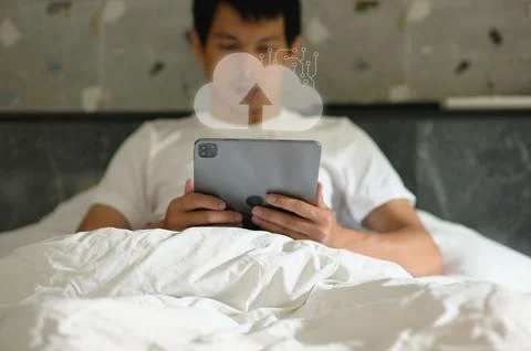 Young boy using tablet with cloud technology icon in bedroom setting Stock Photos