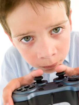 Young boy using videogame controller and concentrating Stock Photos