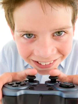 Young boy using videogame controller smiling Stock Photos