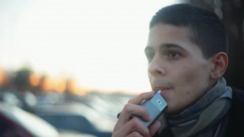 Young boy vaping with help of device for heating tobacco. Alternative of smoking Stock Footage 121483036