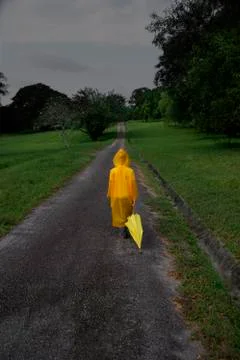 Young boy walking down road with umbrella Stock Photos