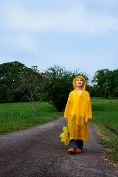 Young boy walking down road with umbrella Stock Photos