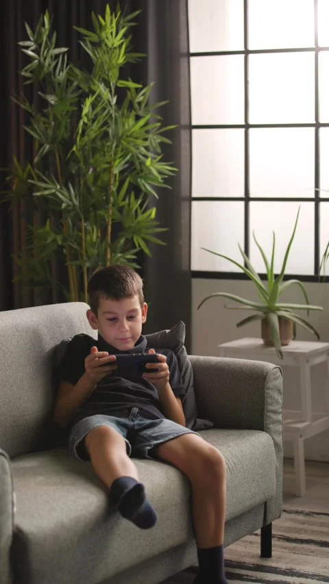 Young Boy Walking to Sofa to Play Smartphone Game Vidéo 344146880