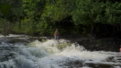 Young boy walks to edge of small scale waterfall drop off Stock Footage 166623553