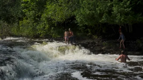 Young boy walks to edge of small scale waterfall drop off Stock Footage 166624237