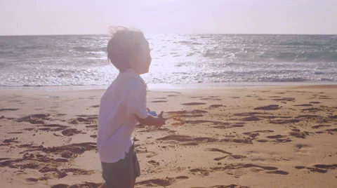 A young boy walks through the sand at the beach Stock Footage 33893691