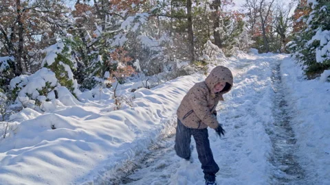 Young boy in warm jacket enjoying winter walk in a beautiful snowy park Video stock 302588874