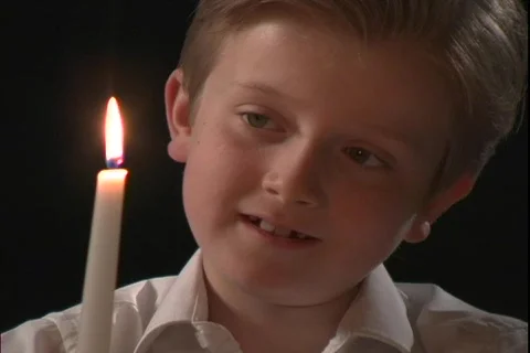 A young boy watches the flame on a candle. Stock Footage