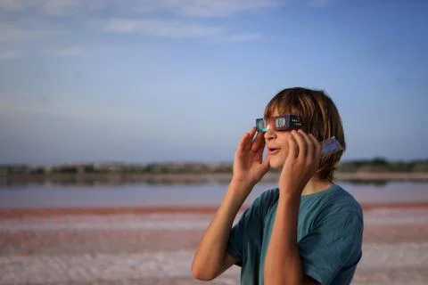 Young boy watches a solar eclipse using protective cardboard glasses, disco.. Stock Photos