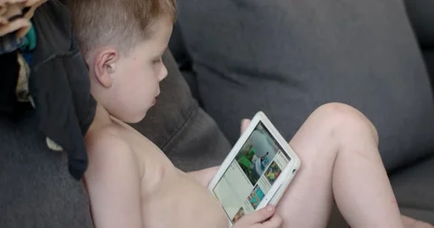 Young Boy Watching Cartoons on a Tablet Computer Sitting on the Couch Stock Footage 64565277