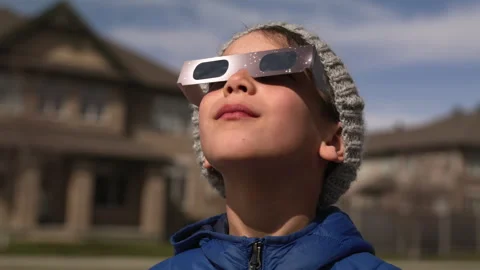 Young boy watching solar eclipse outside home -  close up on face Stock Footage 271315339