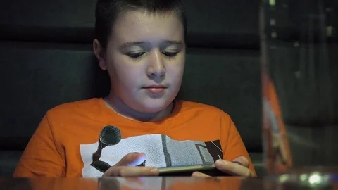 Young boy watching video on smartphone in coffee shop Stock Footage 79385543