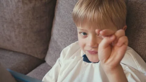 Young boy waving at the camera before using a tablet Stock-Footage 346969360