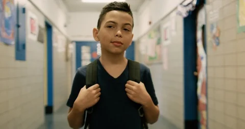 Young boy wearing a backpack walking through a school hallway Stock Footage 108783376