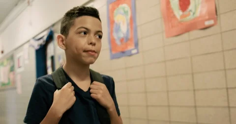 Young boy wearing a backpack walking through a school hallway Stock Footage 108785259