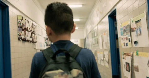Young boy wearing a backpack walking through a school hallway Stock Footage 108785611