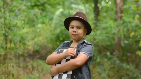 Young Boy Wearing Hat Holding Chessboard and Showing Thumbs Up Stock Footage 343550244