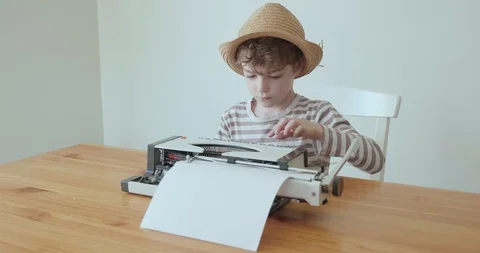 Young boy wearing a hat learning to type on a typewriter 库存影片 127966687