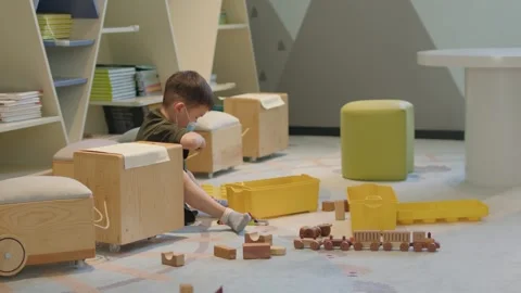 Young Boy Wearing Mask Playing with Wooden Train Toys Indoors Vídeos de archivo 336522480