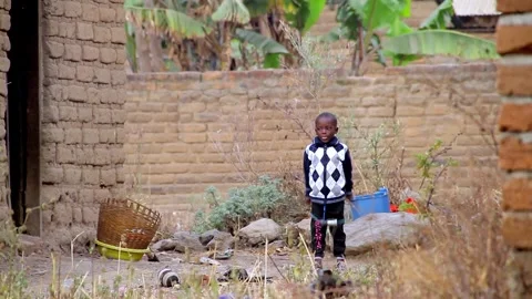 A young boy wearing a patterned sweater and dark pants stands in a dusty, rural Stock Footage 345835061