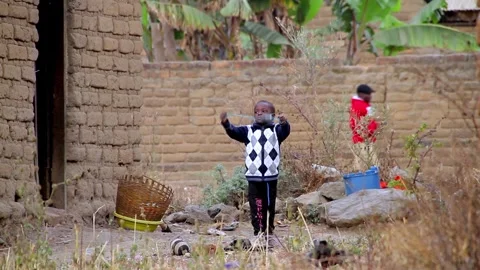 A young boy wearing a patterned sweater and a face mask stands in a rural Stock Footage 345835111