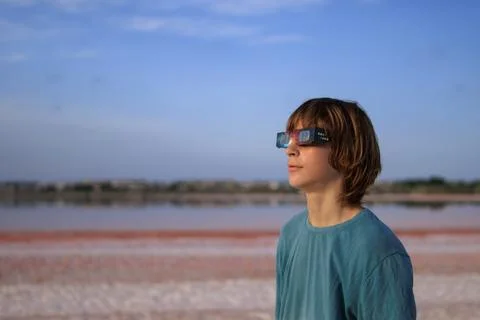 Young boy wearing solar eclipse glasses, observing the celestial event from.. Stock Photos