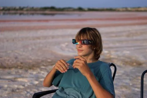 Young boy wearing solar eclipse glasses, looking forward while sitting outd.. Stock Photos