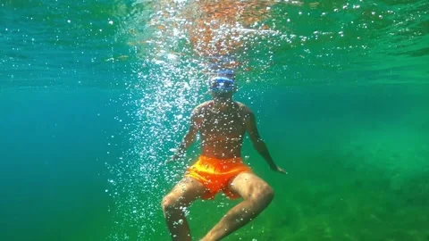 Young boy wearing swimming trunks and snorkel mask diving into clear turquo.. Video stock 321195608