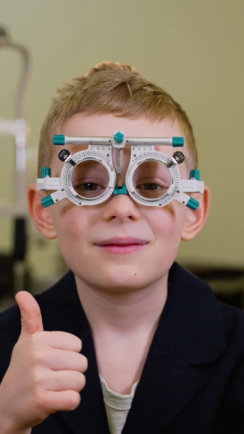 Young boy wearing trial frame doing thumbs up during eye examination Stock Footage 310812170