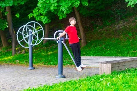 Young Boy While Exercising on Outdoor Air Walker Machine in Park Stockfoto's