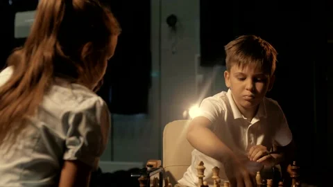 Young boy in white polo playing chess with classmate at competition Stock Footage 156707402