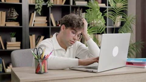 Young boy working on a computer and is disappointed and demotivated because he Stock Footage 316091882