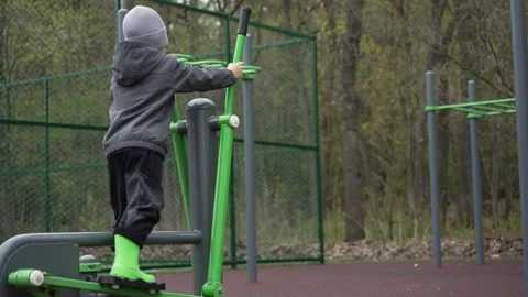Young boy working out on outdoor gym elliptical trainer Stock Footage 334363516