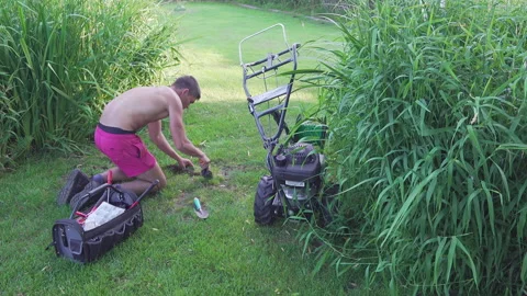 Young boy works on the grass with cable installation for robot lawn mower. Stock Footage 195120903